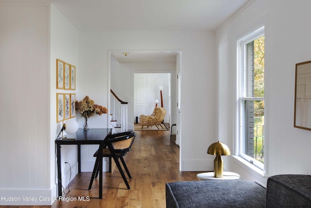 corridor with hardwood / wood-style flooring, plenty of natural light, and wooden walls