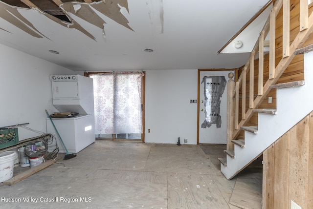 entryway featuring stacked washer and clothes dryer and stairs