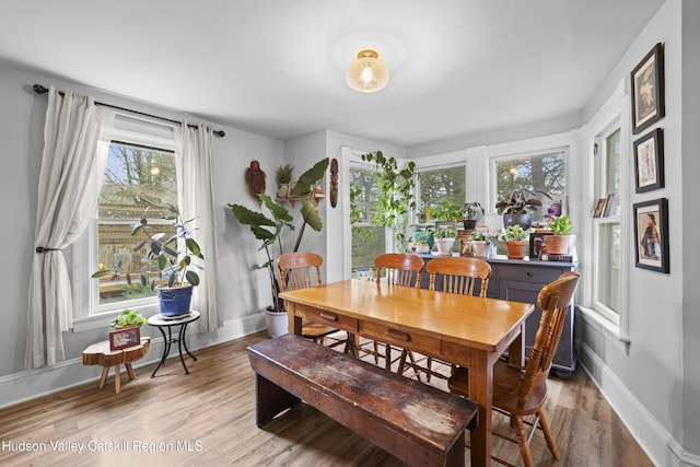 dining space with baseboards and light wood-style flooring