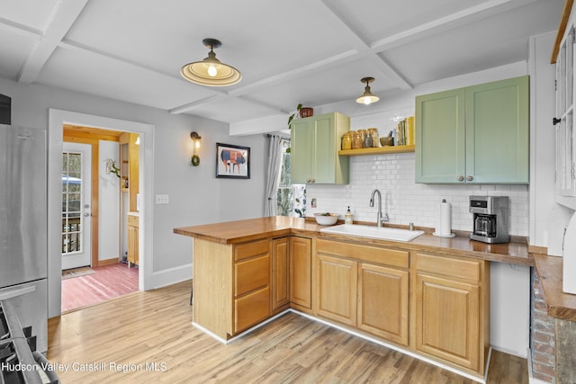 kitchen with a sink, light wood-type flooring, backsplash, coffered ceiling, and freestanding refrigerator