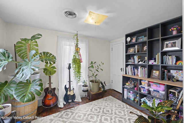 interior space with baseboards, wood finished floors, and visible vents