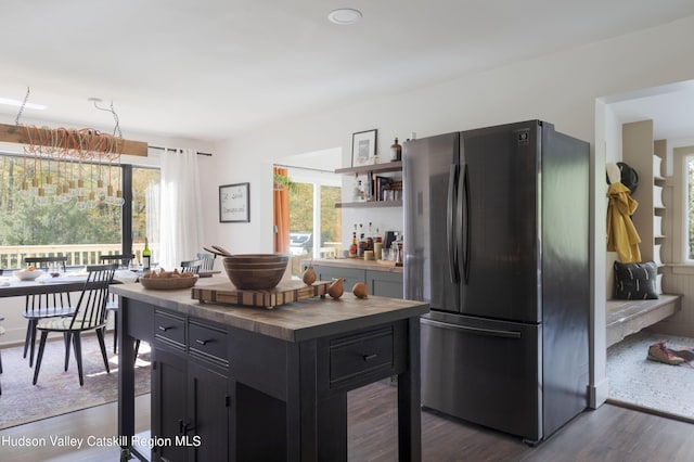 kitchen featuring stainless steel fridge, a center island, and dark wood-type flooring