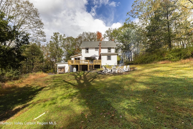 rear view of house featuring a lawn and a deck