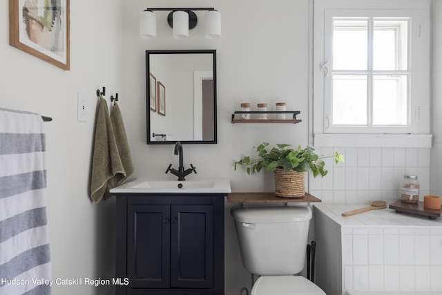 bathroom featuring vanity, a healthy amount of sunlight, and toilet