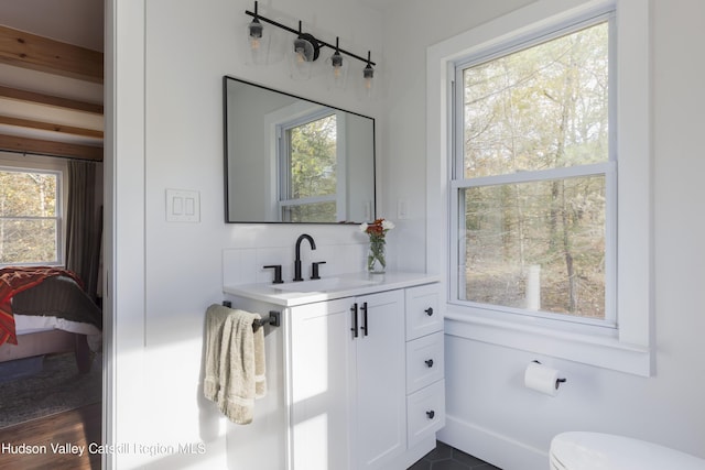 bathroom featuring beam ceiling, vanity, hardwood / wood-style flooring, and a wealth of natural light