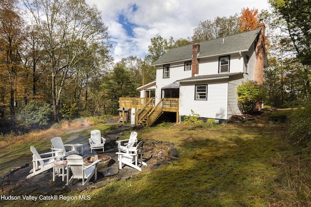 rear view of house with a yard, a fire pit, and a deck