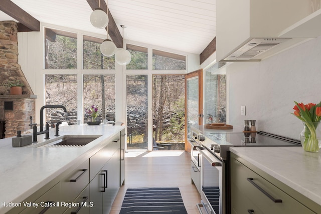 kitchen with sink, hanging light fixtures, range hood, light hardwood / wood-style floors, and high end range