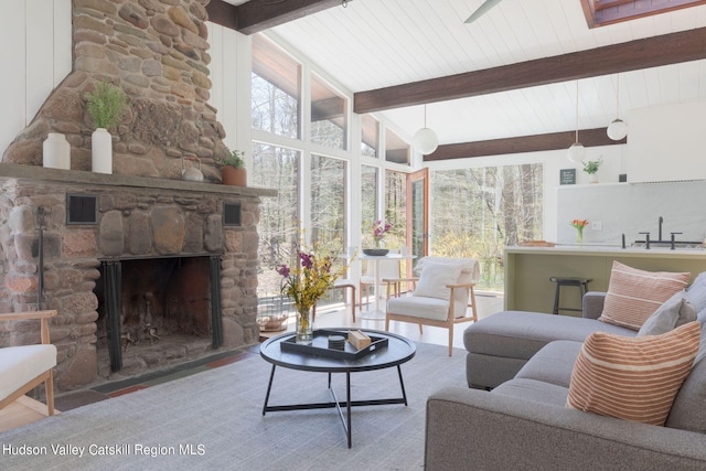 sunroom with vaulted ceiling with beams, sink, and a fireplace