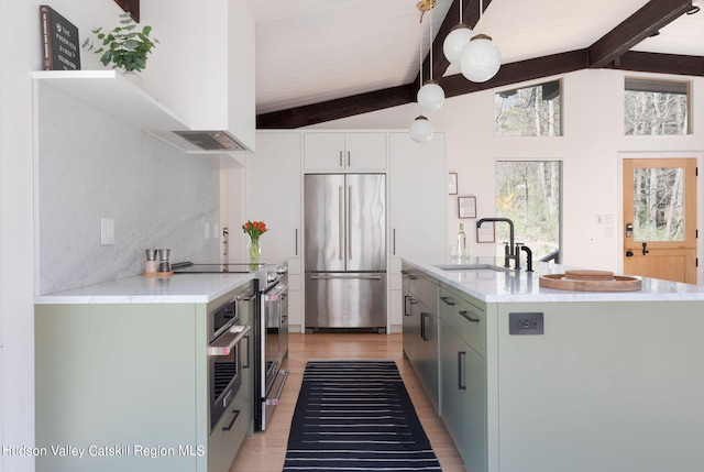 kitchen featuring lofted ceiling with beams, stainless steel appliances, hanging light fixtures, and sink