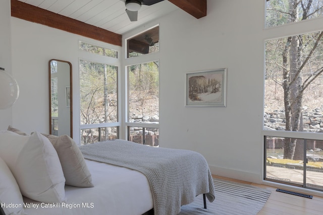 bedroom featuring beam ceiling, multiple windows, ceiling fan, and wood-type flooring