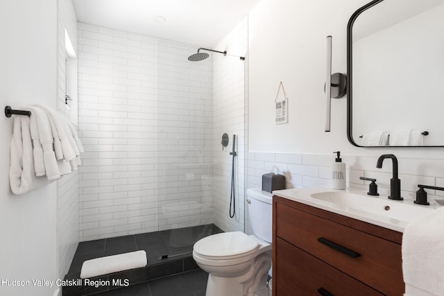 bathroom with vanity, tile patterned floors, toilet, tile walls, and a tile shower