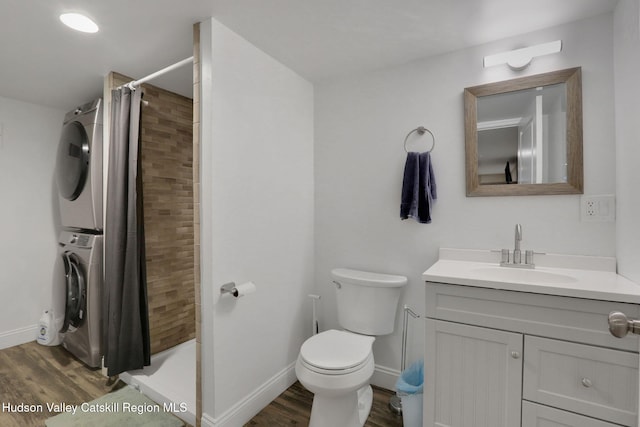 bathroom featuring stacked washer and clothes dryer, toilet, wood finished floors, and a stall shower