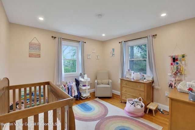 bedroom with baseboards, recessed lighting, wood finished floors, and multiple windows