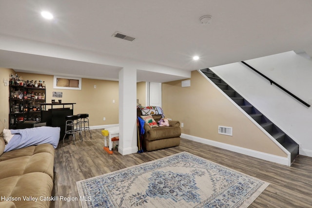 living area with visible vents, a bar, wood finished floors, and baseboards