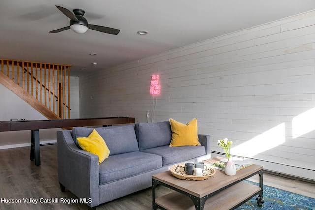 living room featuring wood-type flooring, ceiling fan, and wood walls