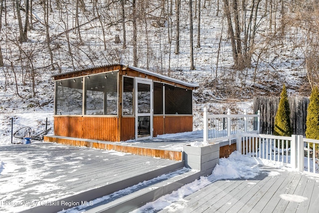 snow covered deck featuring a sunroom