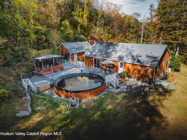 rear view of house featuring a gazebo, a swimming pool side deck, and a lawn