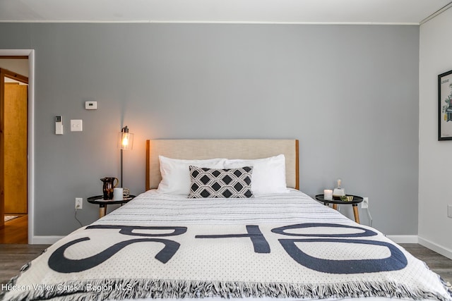 bedroom with ornamental molding and dark hardwood / wood-style flooring