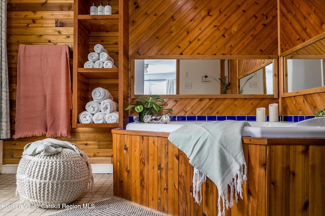 bedroom featuring sink, light tile patterned floors, and wooden walls