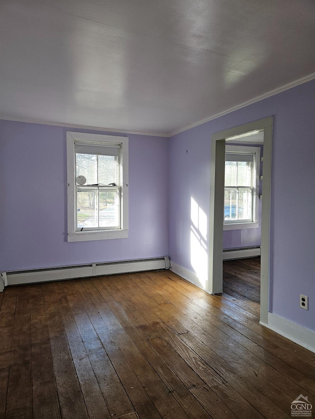 empty room featuring baseboard heating, hardwood / wood-style floors, ornamental molding, and baseboards