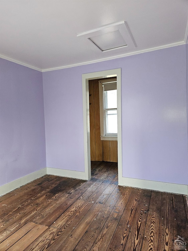spare room featuring hardwood / wood-style floors, crown molding, attic access, and baseboards