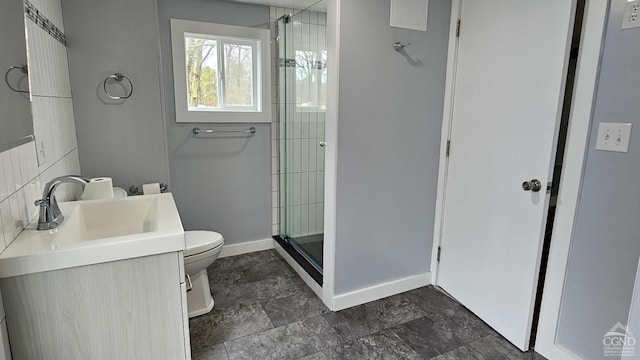 full bathroom featuring baseboards, toilet, a shower stall, vanity, and stone finish flooring
