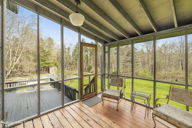 unfurnished sunroom featuring beam ceiling and a wealth of natural light