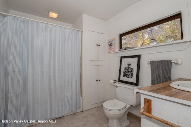 bathroom with toilet, tile patterned floors, curtained shower, and vanity