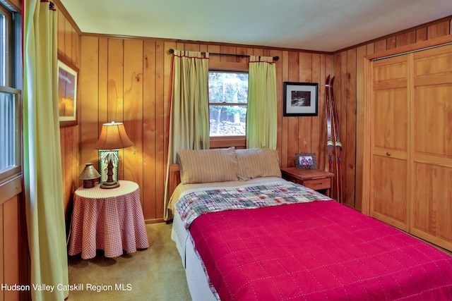 carpeted bedroom featuring a closet and wooden walls