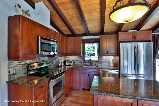 kitchen featuring sink, light hardwood / wood-style flooring, dark stone counters, and appliances with stainless steel finishes