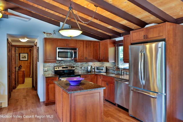 kitchen featuring stainless steel appliances, vaulted ceiling with beams, decorative light fixtures, a kitchen island, and light wood-type flooring