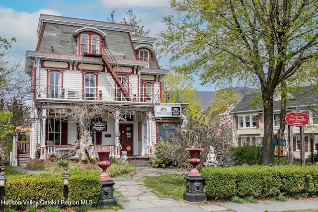 victorian home with a porch, a balcony, and mansard roof