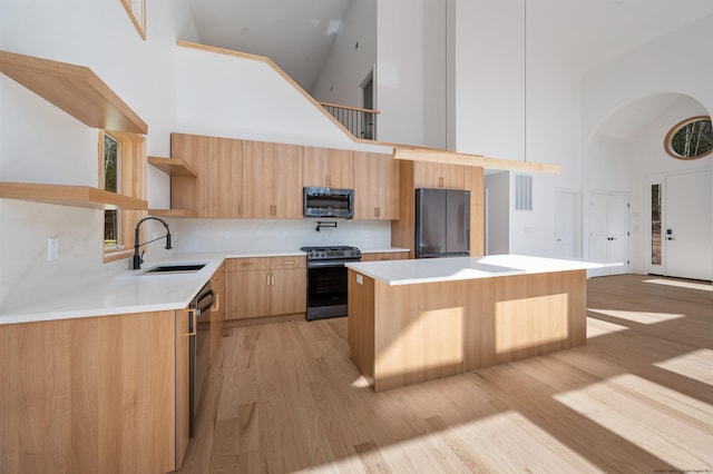 kitchen with a center island, sink, high vaulted ceiling, and stainless steel appliances