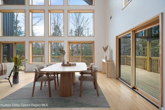 dining space with a towering ceiling and light wood-type flooring