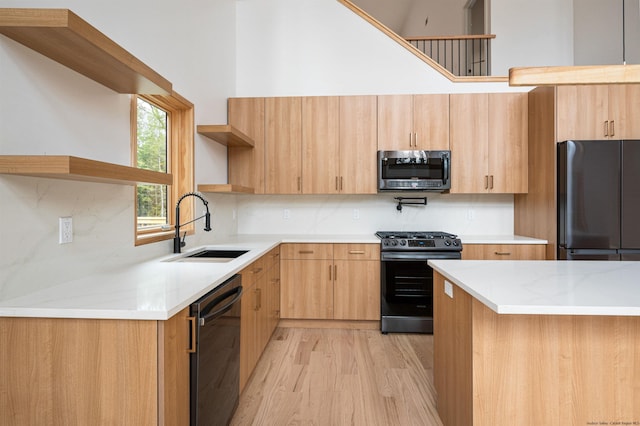 kitchen featuring black appliances, sink, light hardwood / wood-style flooring, decorative backsplash, and light stone countertops