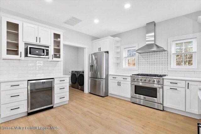 26 Debbie Dr, Athens, NY 12015 - kitchen featuring wall chimney exhaust hood, light countertops, beverage cooler, stainless steel appliances, and washer and clothes dryer