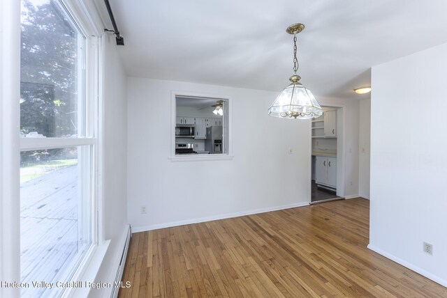 94 Tammany St, Kingston, NY 12401 - unfurnished dining area with hardwood / wood-style floors, baseboards, healthy amount of natural light, and a chandelier