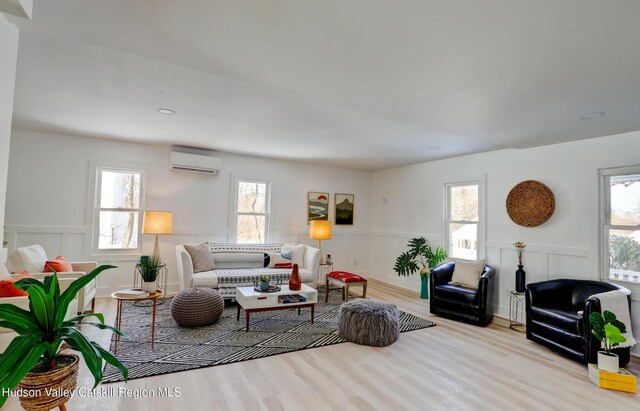 living room with light wood-type flooring and a wall unit AC