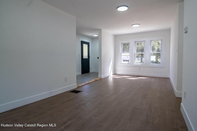 spare room with baseboards, visible vents, and dark wood-type flooring