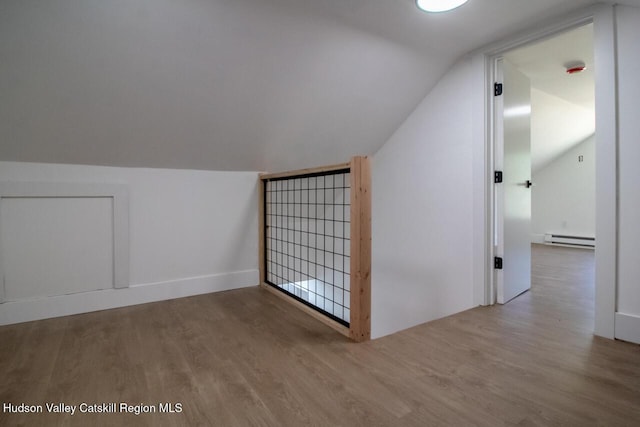 additional living space with wood finished floors, a baseboard radiator, and lofted ceiling