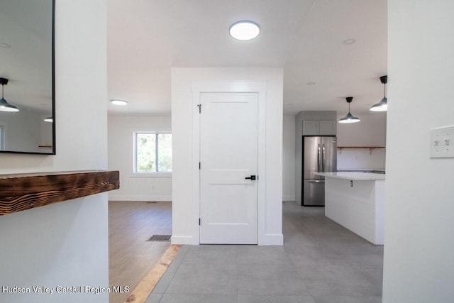 hallway featuring baseboards, visible vents, and light tile patterned floors