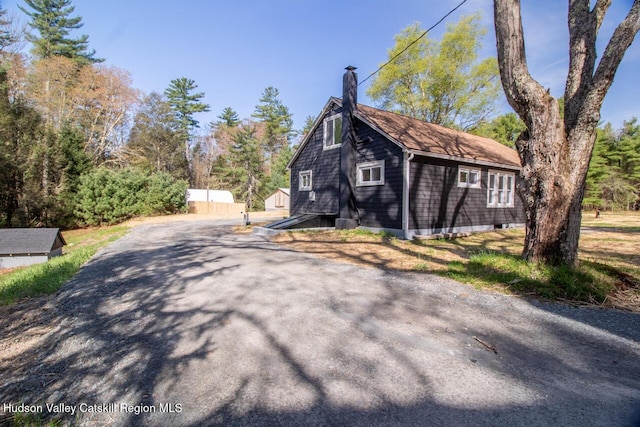 view of home's exterior featuring a chimney and aphalt driveway