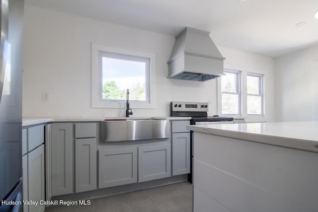 kitchen featuring a sink, gray cabinetry, light tile patterned floors, custom exhaust hood, and stainless steel appliances