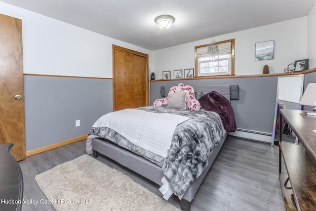 bedroom with baseboards, wood finished floors, and baseboard heating