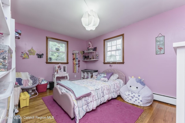 bedroom featuring a baseboard heating unit and wood finished floors