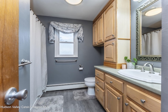 bathroom featuring wood finished floors, toilet, vanity, a baseboard heating unit, and baseboards