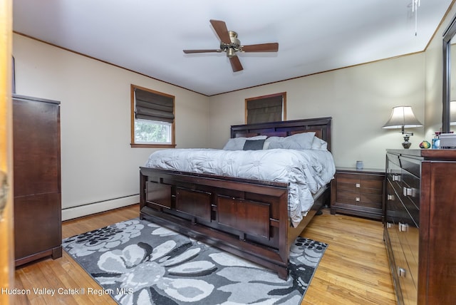 bedroom featuring baseboard heating, wood finished floors, and ceiling fan