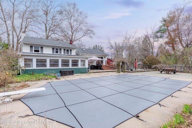 view of swimming pool with fence, a diving board, a patio, a covered pool, and a sunroom