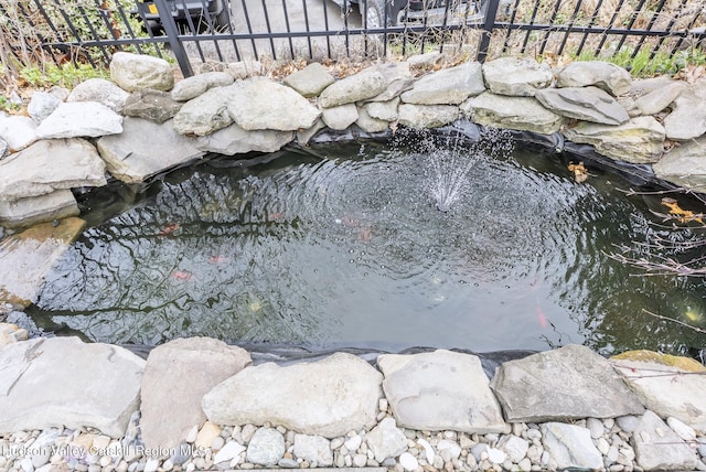 details featuring fence and a garden pond