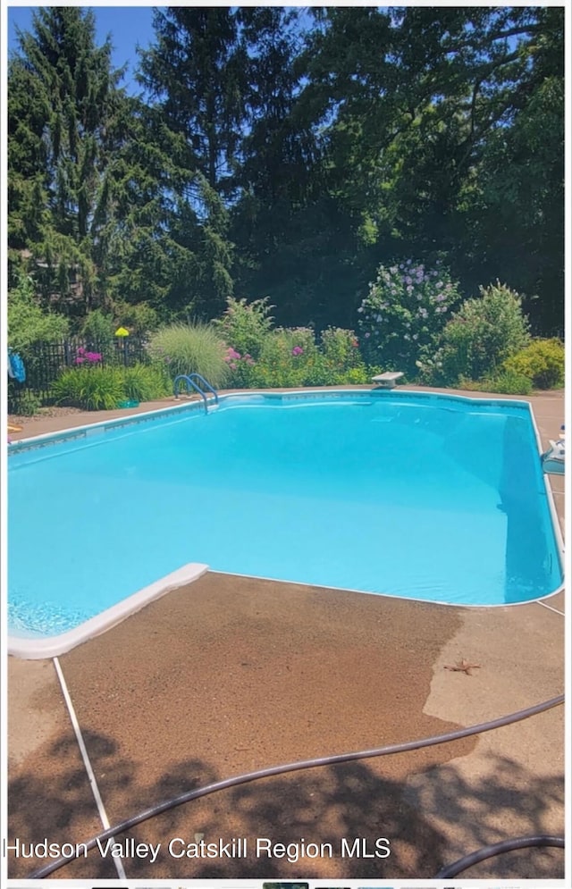 outdoor pool with a patio area and a diving board